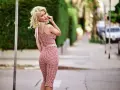 Kobieta w czerwono-białym kostiumie w kratkę, z burzą blond włosów, przywołuje **efekt Marilyn Monroe** na ulicy.