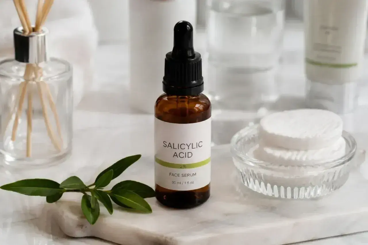 Serum z kwasem salicylowym na niedoskonałości skóry. W buteleczce z pipetą, obok wacików i gałązki.