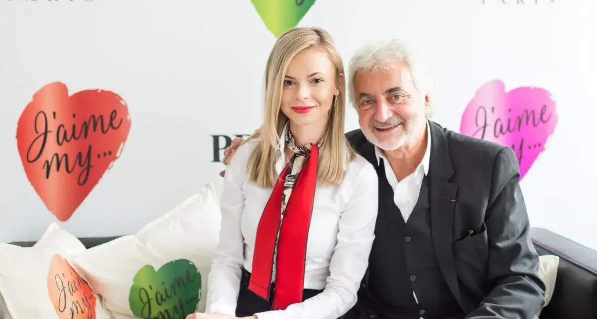 Franck Provost i uśmiechnięta kobieta siedzą na kanapie. W tle logo Franck Provost i serca z napisem "J'aime my...".