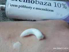 Krem półtłusty z mocznikiem, cremobaza 10%, nałożony na skórę dłoni. Tubka produktu widoczna w tle.