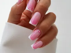 Delikatne french nails z różowym ombre i ozdobą w postaci drobnych kwiatków.