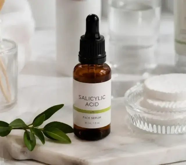 Serum z kwasem salicylowym na niedoskonałości skóry. W buteleczce z pipetą, obok wacików i gałązki.