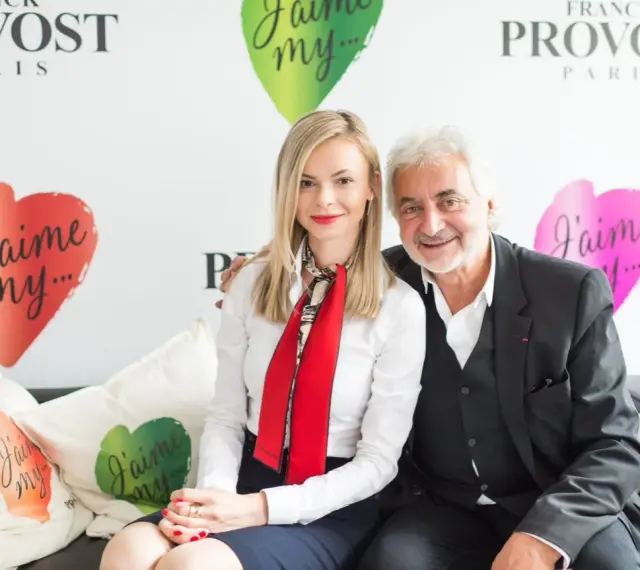 Franck Provost i uśmiechnięta kobieta siedzą na kanapie. W tle logo Franck Provost i serca z napisem "J'aime my...".