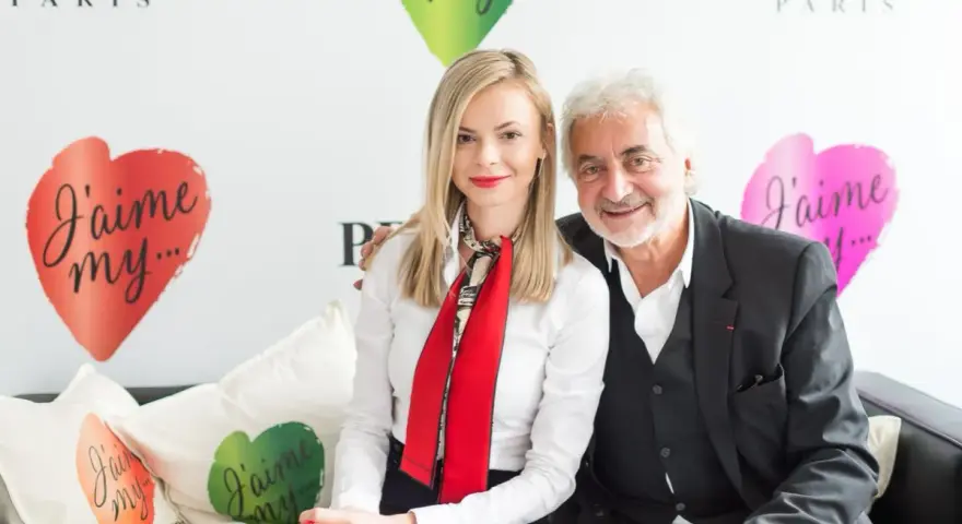 Franck Provost i uśmiechnięta kobieta siedzą na kanapie. W tle logo Franck Provost i serca z napisem "J'aime my...".