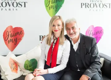 Franck Provost i uśmiechnięta kobieta siedzą na kanapie. W tle logo Franck Provost i serca z napisem "J'aime my...".